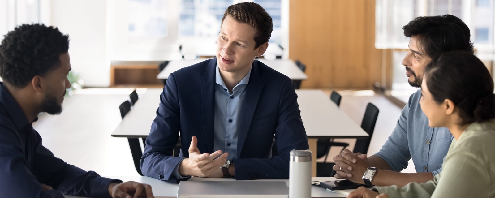 Ein Mann leitet ruhig und präsent ein Gespräch am Tisch